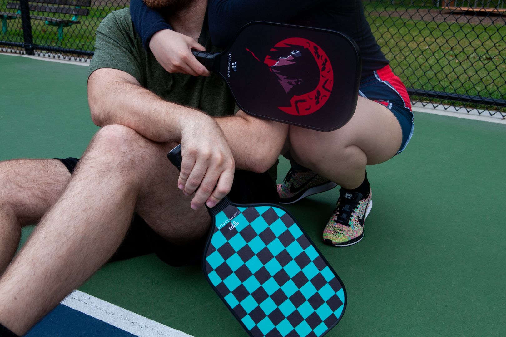 A couple holding TokyoPaddles pickleball paddles. The woman is holding an Itachi Inspired paddle. The man is holding a Tanjiro Inspired paddle.