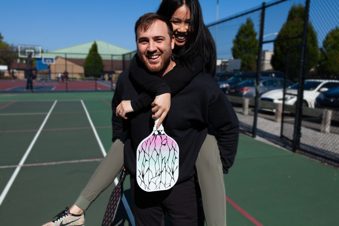 Woman on Mans back holding a shinobu pickleball paddle and the man holding an akatsuki pickleball paddle from TokyoPaddles.